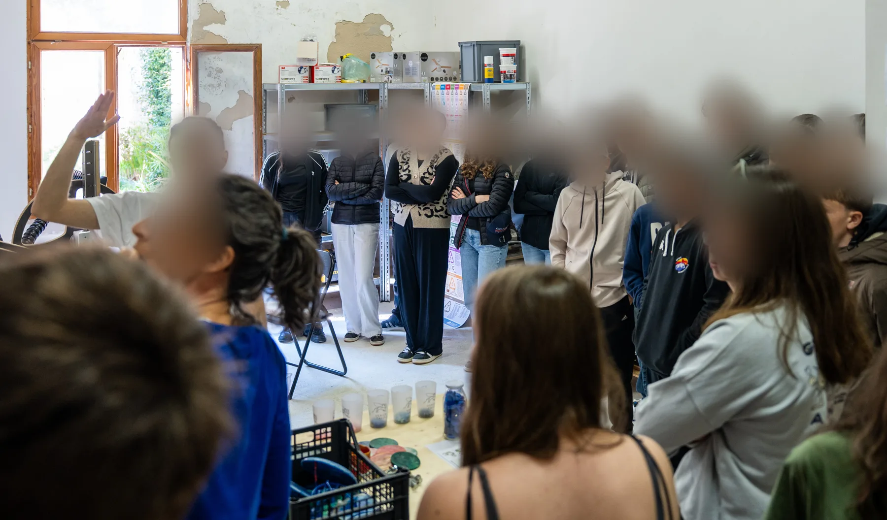 Une classe de lycée réunie dans l'atelier d'une association vénitienne, autour d'une table de matériel de récupération