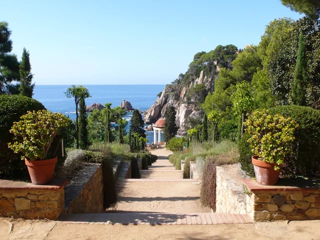 Allée du jardin botanique descendant entre les cyprès vers un pavillon et la mer