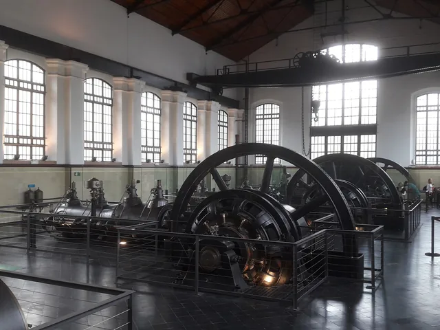 Salle des machines d'une station de pompage, grand volant d'acier et hautes verrières