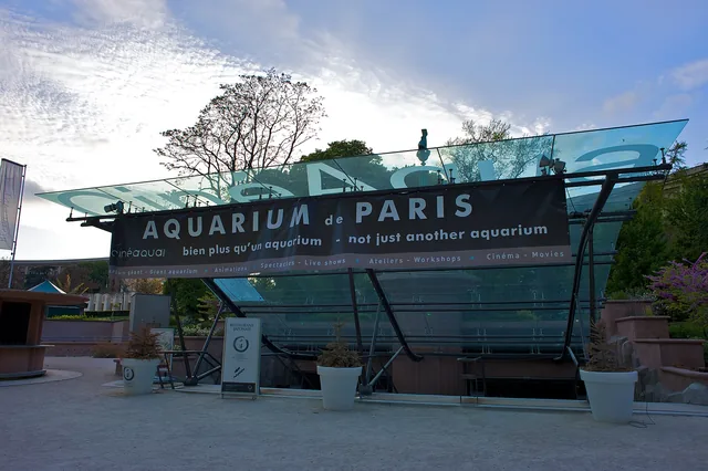 Entrée vitrée de l'aquarium sous les arbres du parc, avec son enseigne