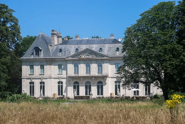 Château du XVIIIe siècle en pierre claire, prairie de graminées au premier plan