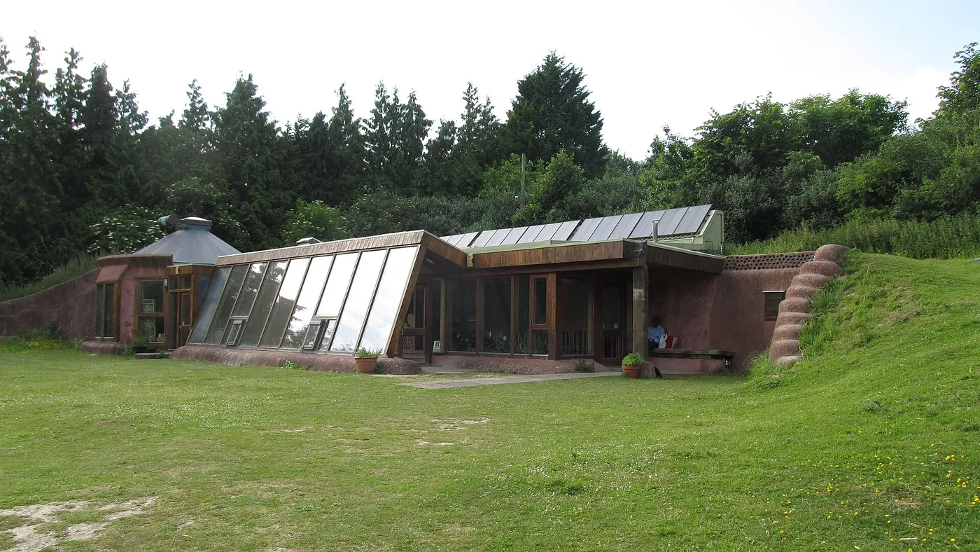 Voyage scolaire durable à Brighton : bâtiment semi-enterré à façade vitrée et panneaux solaires, au bord d'une prairie