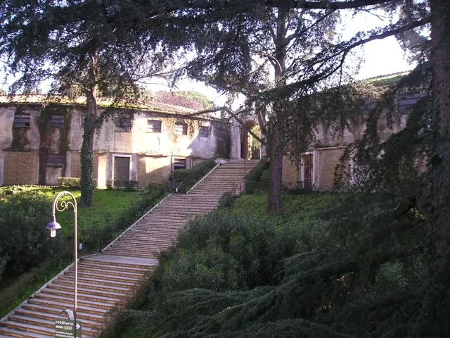 Allée bordée de végétation et pavillon ancien du parc zoologique