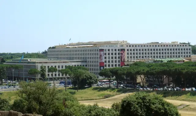Le bâtiment du siège vu depuis un parc planté de pins