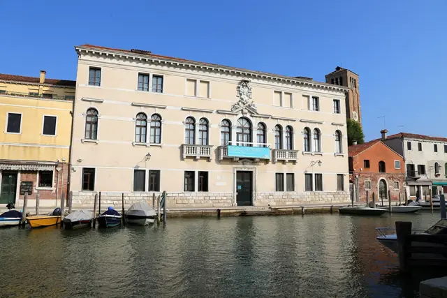 Le palais de pierre claire du musée au bord du canal, barques amarrées