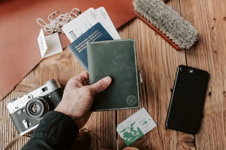 Une main tient un passeport, près de billets de voyage