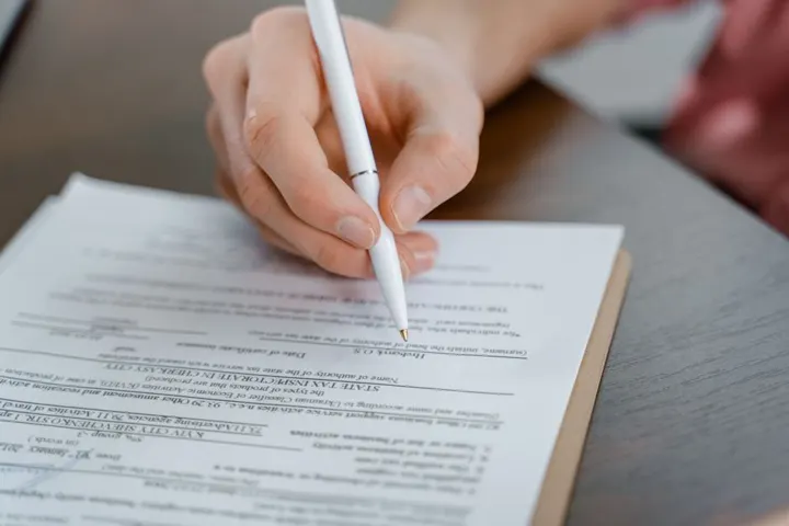 Une main remplit un formulaire au stylo