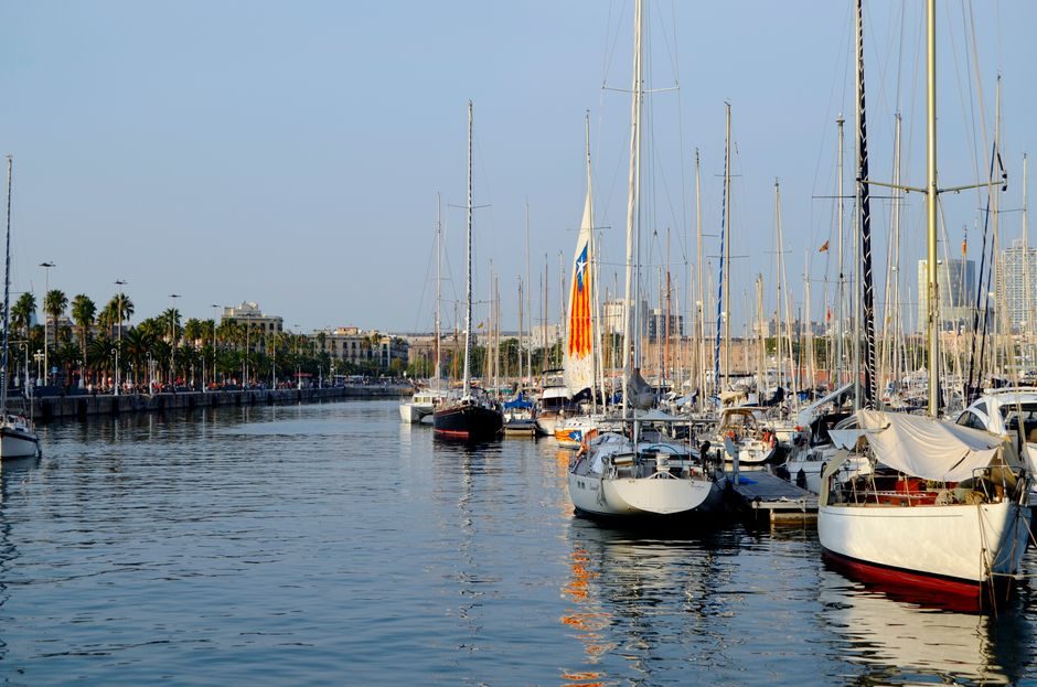 Voiliers amarrés au Port Vell, immeubles de la ville derrière