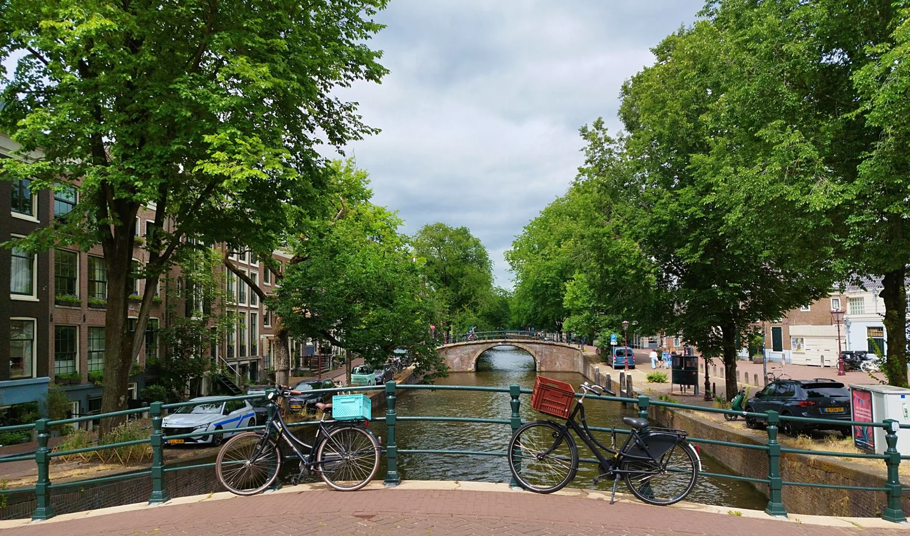 Vélos garés sur un pont au-dessus d'un canal bordé d'arbres et de maisons anciennes