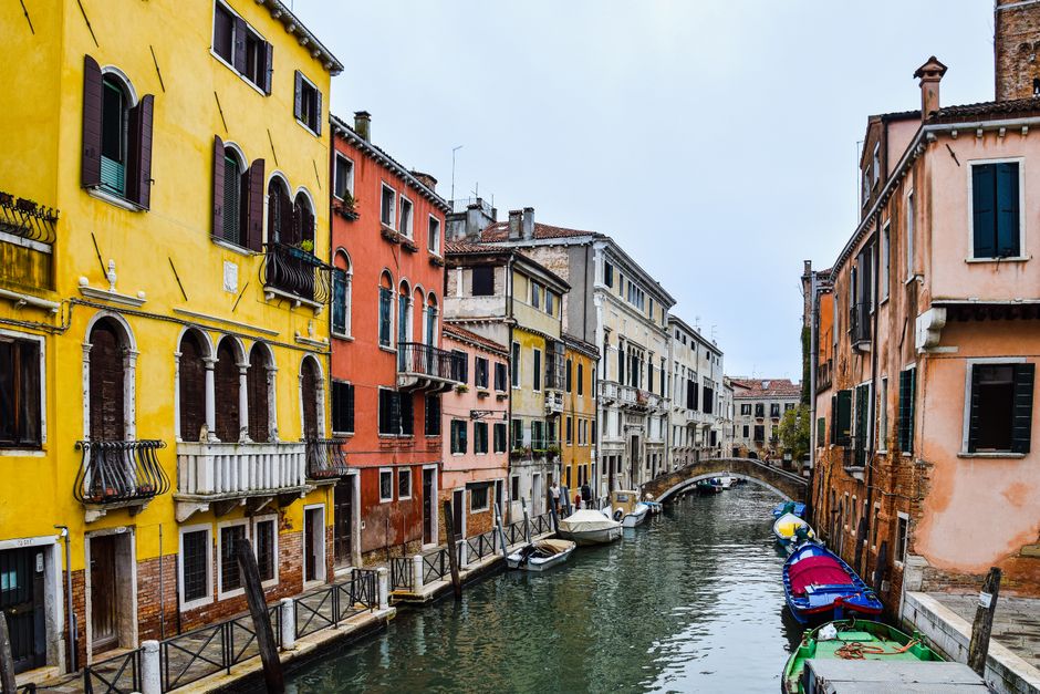 Un canal vénitien bordé de façades jaunes et orangées, barques amarrées